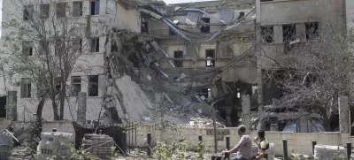 People pass in front the Syrian Defense Ministry building which on Wednesday was heavily damaged by Israeli airstrikes in Damascus, Syria, Thursday, July 17, 2025. (AP Photo/Ghaith Alsayed)