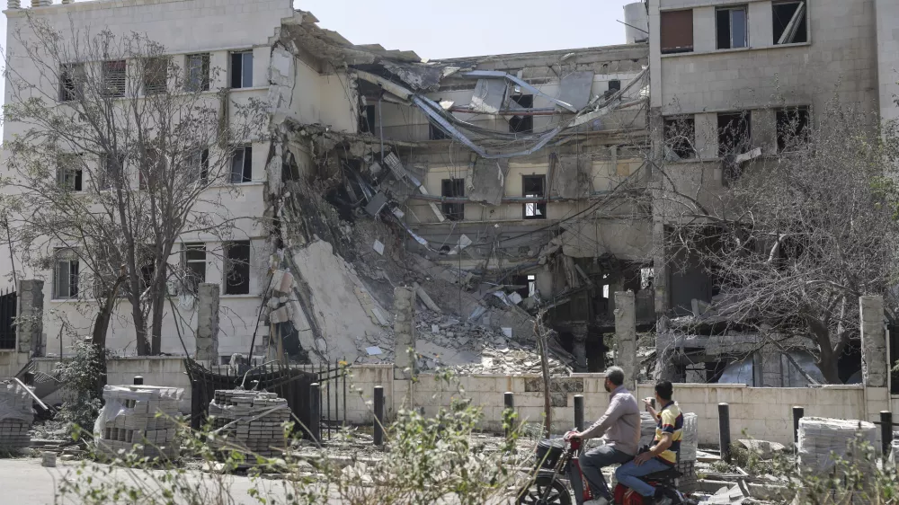 People pass in front the Syrian Defense Ministry building which on Wednesday was heavily damaged by Israeli airstrikes in Damascus, Syria, Thursday, July 17, 2025. (AP Photo/Ghaith Alsayed)