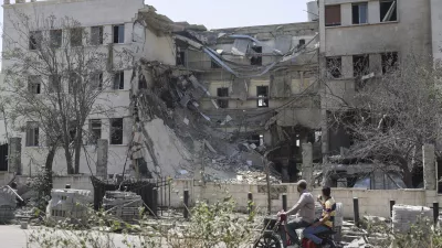 People pass in front the Syrian Defense Ministry building which on Wednesday was heavily damaged by Israeli airstrikes in Damascus, Syria, Thursday, July 17, 2025. (AP Photo/Ghaith Alsayed)
