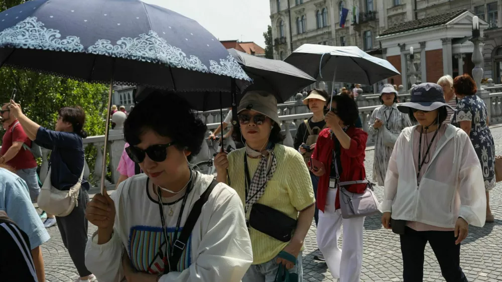 11.06.2025. Azijski turisti s senčniki v Ljubljani. Vročinski val. Foto: Bojan Velikonja 