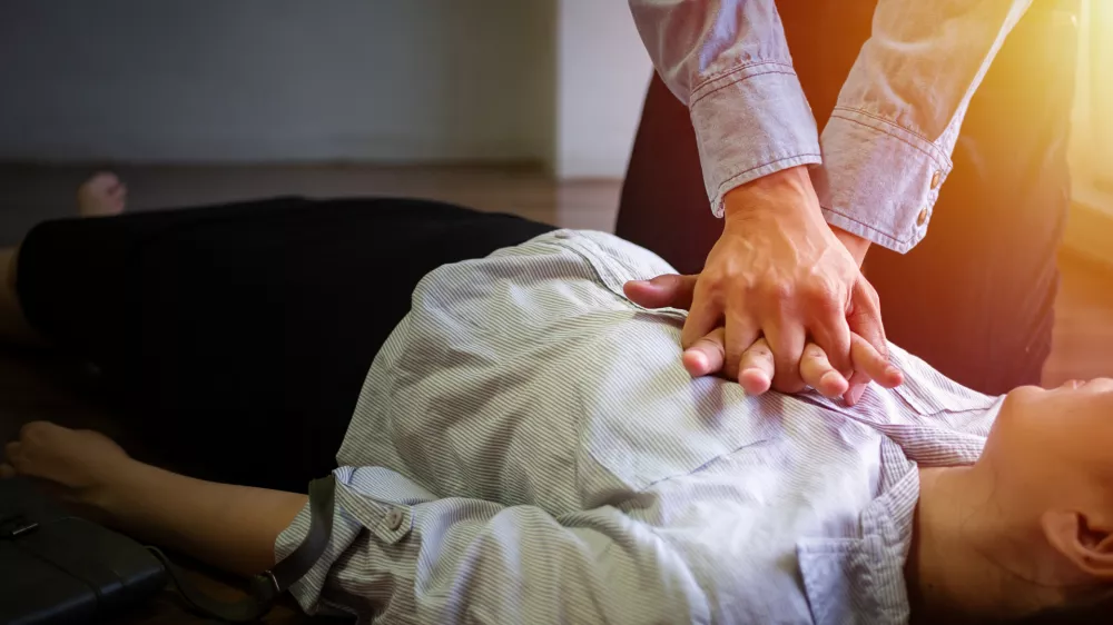 volunteer office man use hand pump on chest for first aid emergency CPR on heart attack woman unconscious, try to resuscitation patient woman at work