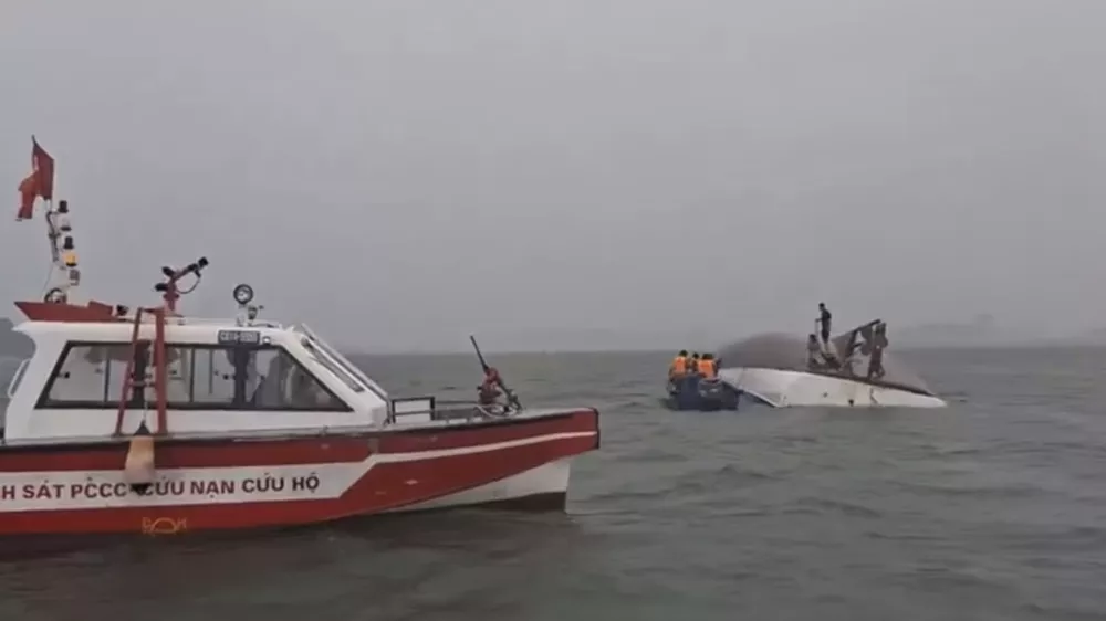 This image from a video provided by QDND shows people on a capsized tourist boat being rescued in Ha Long Bay, Vietnam on Saturday, July 19, 2025. (QDND via AP)