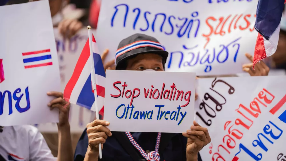 Bangkok, 20 July 2025 – A protester holds a sign reading "Stop violating Ottawa Treaty" during a nationalist demonstration outside the Cambodian Embassy in Bangkok. Protesters gathered outside the Royal Embassy of Cambodia to denounce Cambodia's alleged use of landmines on Thai territory, following the injury of Thai soldiers near the Chong Bok border area. Authorities claim the mines, recently discovered beyond Cambodia's military line, violate the Ottawa Convention.Bangkok, 20 juillet 2025 – Une manifestante brandit une pancarte « Stop violating Ottawa Treaty » lors d'un rassemblement nationaliste devant l'ambassade du Cambodge a Bangkok. Des manifestants se sont rassembles devant l'Ambassade Royale du Cambodge pour denoncer l'usage presume de mines antipersonnel par le Cambodge sur le territoire thailandais, apres la blessure de soldats thailandais pres de la frontiere de Chong Bok. Les autorites affirment que les mines, recemment decouvertes au-dela de la ligne militaire cambodgienne, enfreignent la Convention d'Ottawa.