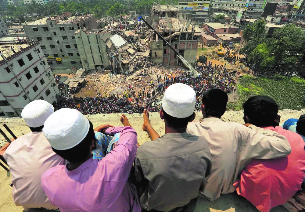 ﻿People watch as rescue workers continue their operations at the collapsed Rana Plaza building in Savar, 30 km (19 miles) outside Dhaka April 25, 2013. Survivors from the garment factory that collapsed in Bangladesh killing at least 228 people described on Thursday a deafening bang and tremors before the eight-floor building crashed down under them. REUTERS/Stringer (BANGLADESH - Tags: BUSINESS DISASTER TPX IMAGES OF THE DAY)