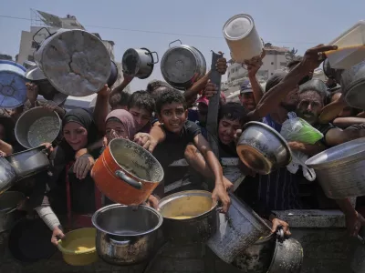 Palestinians struggle to get donated food at a community kitchen, in Gaza City, northern Gaza Strip, Saturday, July 26, 2025. (AP Photo/Abdel Kareem Hana)