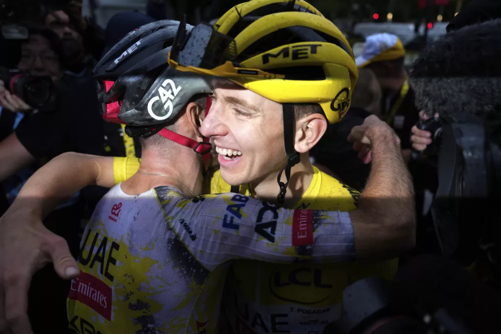 Tour de France winner Tadej Pogacar of Slovenia is hugged by a teammate after the twenty-first stage of the Tour de France cycling race over 132.3 kilometers (82.1 miles) with start in Mantes-la-Ville and finish on the Champs-Elysees in Paris, France, Sunday, July 27, 2025. (AP Photo/Mosa'ab Elshamy)