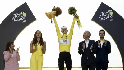 Cycling - Tour de France - Stage 21 - Mantes-la-Ville to Paris - Paris, France - July 27, 2025 UAE Team Emirates XRG's Tadej Pogacar celebrates on the podium wearing the yellow jersey after winning the Tour de France, as Paris' mayor Anne Hidalgo applauds REUTERS/Benoit Tessier