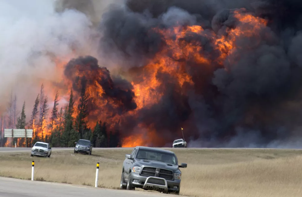 ﻿A wildfire burns south of Fort McMurray, Alberta, near Highway 63 on Saturday, May 7, 2016. Canadian officials hoped to complete the mass evacuation of work camps north of Alberta's main oil sands city of Fort McMurray on Saturday, fearing the growing wildfire could double in size and reach a major oil sands mine and even the neighboring province of Saskatchewan. (Jonathan Hayward /The Canadian Press via AP) MANDATORY CREDIT
