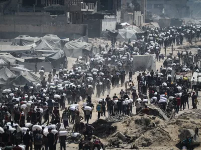 27 July 2025, Palestinian Territories, Gaza City: Palestinians carry sacks of flour from a humanitarian aid convoy, as they make their way along al-Rashid street. Against the backdrop of a looming hunger crisis in the Gaza Strip, large-scale aid deliveries reached the besieged and embattled coastal area for the first time in months on Sunday. Photo: Omar Ashtawy/APA Images via ZUMA Press Wire/dpa