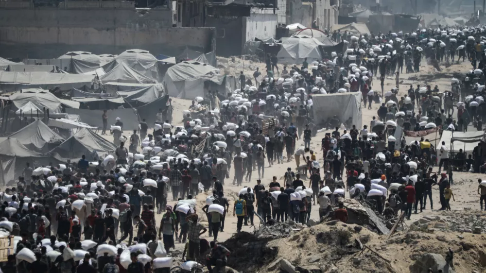 27 July 2025, Palestinian Territories, Gaza City: Palestinians carry sacks of flour from a humanitarian aid convoy, as they make their way along al-Rashid street. Against the backdrop of a looming hunger crisis in the Gaza Strip, large-scale aid deliveries reached the besieged and embattled coastal area for the first time in months on Sunday. Photo: Omar Ashtawy/APA Images via ZUMA Press Wire/dpa
