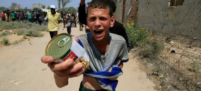 A Palestinian youth holds a can of chickpeas from an aid package dropped from an airplane, amid a hunger crisis, in Zawayda, in the central Gaza Strip, July 28, 2025. REUTERS/Hatem Khaled