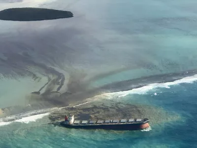 ﻿This photo taken and provided by Eric Villars shows oil leaking from the MV Wakashio, a bulk carrier ship that recently ran aground off the southeast coast of Mauritius, Friday, Aug. 7, 2020. Anxious residents of the Indian Ocean island nation of Mauritius are stuffing fabric sacks with sugar cane leaves to create makeshift oil spill barriers as tons of fuel leak from a grounded ship. The government has declared an environmental emergency and France says it is sending help from its nearby Reunion island. (Eric Villars via AP)