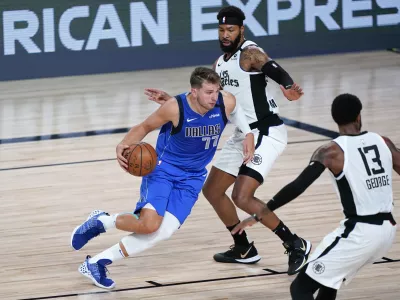 Aug 21, 2020; Lake Buena Vista, Florida, USA; Dallas Mavericks' Luka Doncic (77) drives against Los Angeles Clippers' Marcus Morris Sr., center, and Paul George (13) during the second half in a NBA basketball first round playoff game at AdventHealth Arena. Mandatory Credit: Ashley Landis/Pool Photo-USA TODAY Sports