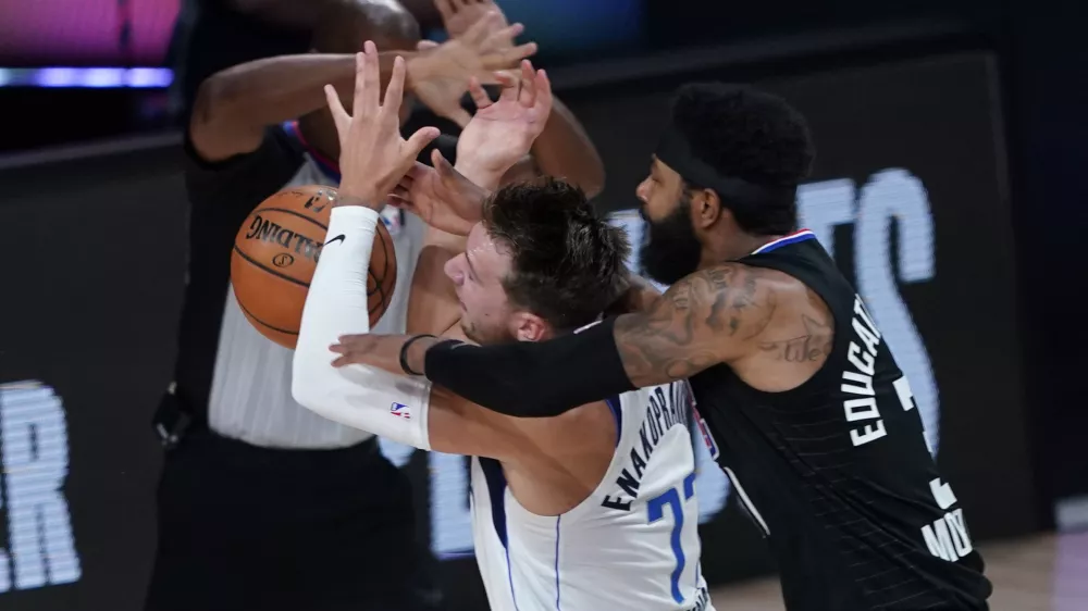 Dallas Mavericks' Luka Doncic (77) is fouled by Los Angeles Clippers' Marcus Morris Sr. during the first half of an NBA first round playoff game Sunday, Aug. 30, 2020, in Lake Buena Vista, Fla. (AP Photo/Ashley Landis)