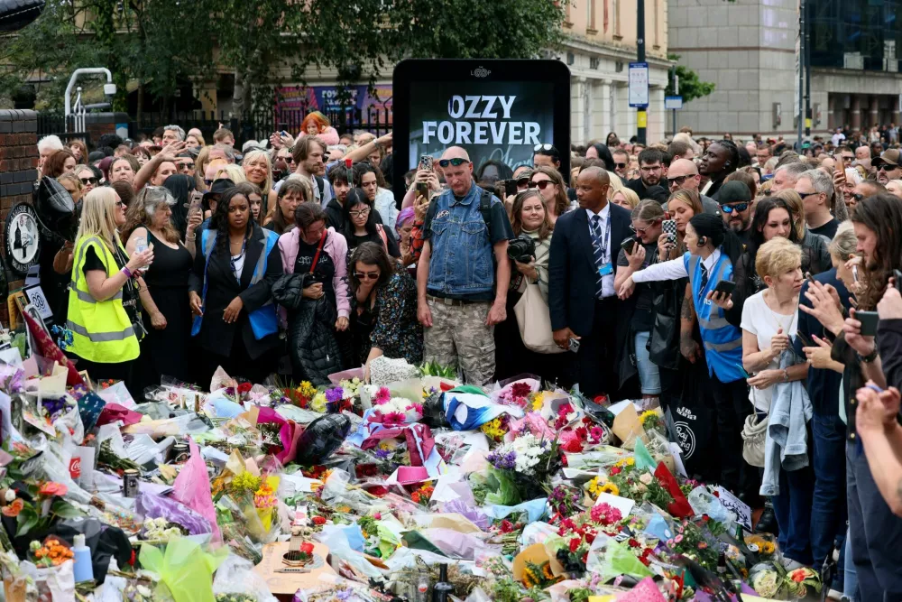 People gather around tributes placed at the Black Sabbath Bridge, named in honour of the heavy metal band, on the day of the funeral cortege of Ozzy Osbourne, its former frontman, in Birmingham, Britain, July 30, 2025. REUTERS/Jack Taylor