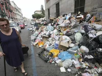 A woman walks past piles of trash piled on a sidewalk in Naples May 17, 2008. A resurgent trash crisis in Naples and squabbling over immigration pose challenges to newly elected Prime Minister Silvio Berlusconi as he finalises a sweeping security and economic reform package. Berlusconi is moving his cabinet to the troubled port city of Naples on Wednesday to agree on the reforms, the first major initiative of his conservative government since it came to power last month. Picture taken May 17, 2008. REUTERS/Renato Nicois/Agnfoto (ITALY)