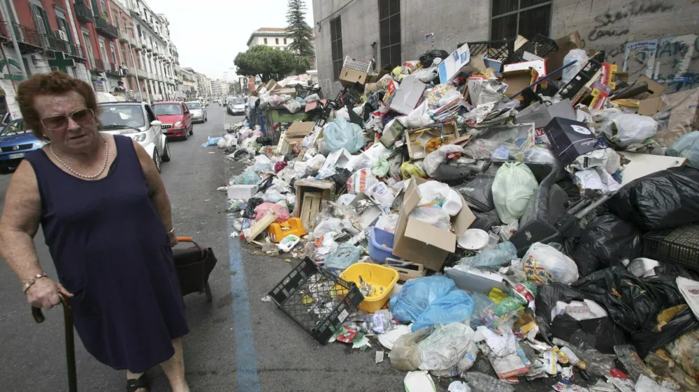 A woman walks past piles of trash piled on a sidewalk in Naples May 17, 2008. A resurgent trash crisis in Naples and squabbling over immigration pose challenges to newly elected Prime Minister Silvio Berlusconi as he finalises a sweeping security and economic reform package. Berlusconi is moving his cabinet to the troubled port city of Naples on Wednesday to agree on the reforms, the first major initiative of his conservative government since it came to power last month. Picture taken May 17, 2008. REUTERS/Renato Nicois/Agnfoto (ITALY)