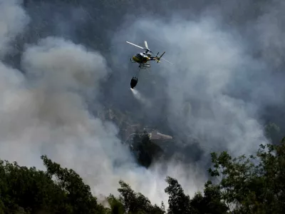A helicopter flies after unloading water during efforts to battle a wildfire in the Arouca region, Portugal, July 30, 2025. REUTERS/Violeta Santos Moura   TPX IMAGES OF THE DAY