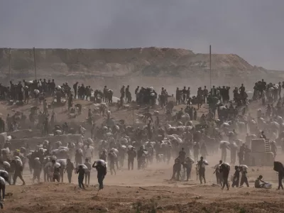 Palestinians carry humanitarian aid packages near a Gaza Humanitarian Foundation distribution center operated by the U.S.-backed organization, in Netzarim, central Gaza Strip, Monday, Aug. 4, 2025. (AP Photo/Abdel Kareem Hana)