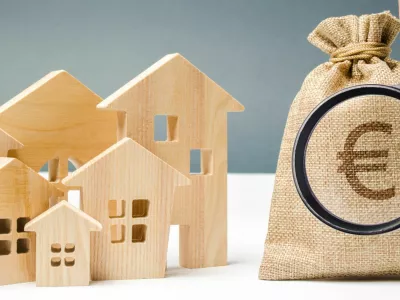 ﻿Bag with money and euro sign and wooden houses. Financing in the country. Investing money in real estate. Saving and accumulation of money. Mortgage. Buying a home. Property sale. City budget.