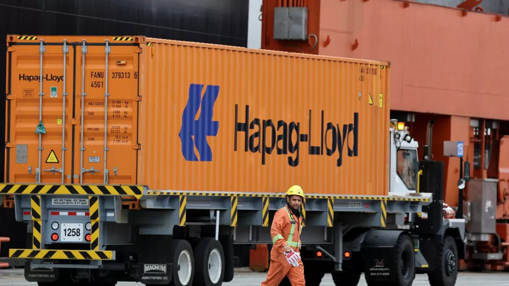 A worker walks near a truck carrying a container at the Centerm container ship terminal at the Port of Vancouver in Vancouver, British Columbia, Canada August 3, 2025. REUTERS/Chris Helgren