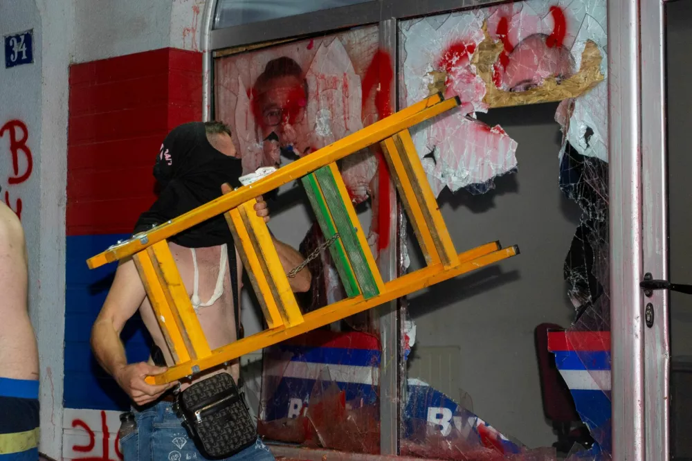 A demonstrator breaks a window of the Serbian Progressive Party (SNS) ruling party headquarters during a standoff between ruling party supporters and anti-government protesters in Novi Sad, Serbia, August 14, 2025. REUTERS/Andrej Hlozan