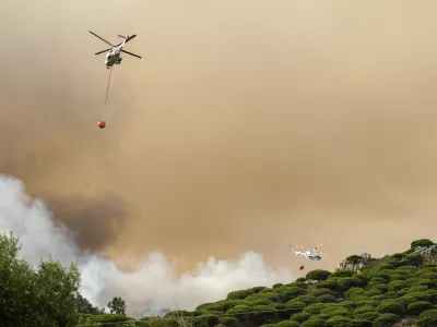 Firefighting helicopters drop water to extinguish a blaze in Torre de la Peña, southern Spain, Tuesday, Aug. 5, 2025. (Nono Rico/Europa Press via AP)