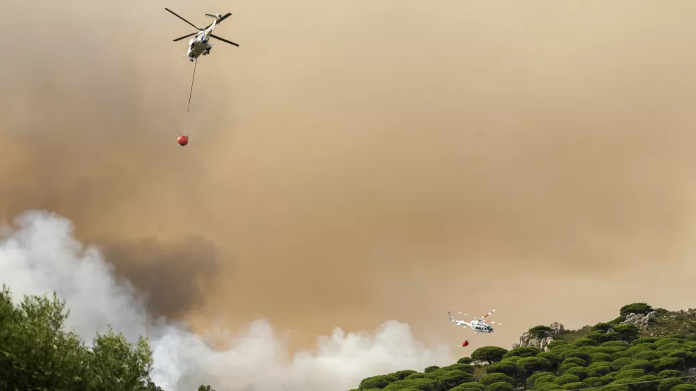 Firefighting helicopters drop water to extinguish a blaze in Torre de la Peña, southern Spain, Tuesday, Aug. 5, 2025. (Nono Rico/Europa Press via AP)