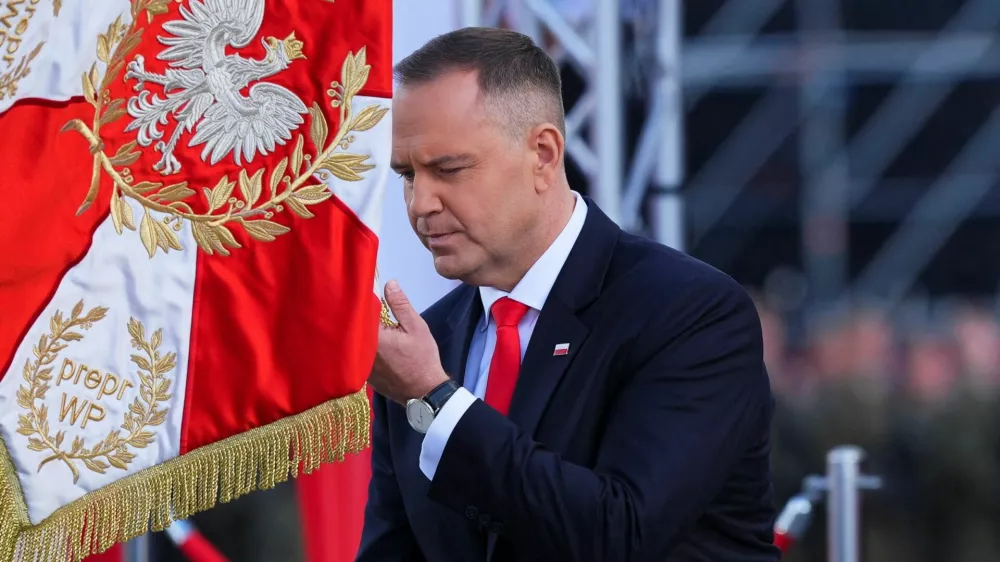 Newly sworn-in Polish President Karol Nawrocki kneels down in front of a flag as he attends the ceremony of accepting the sovereignty over the Armed Forces for the five-year term, in Warsaw, Poland, August 6, 2025. REUTERS/Aleksandra Szmigiel