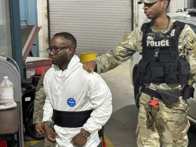 Sgt. Quornelius Radford, a suspect in the shooting of five soldiers at Fort Stewart, is escorted by military police into a booking room at the Liberty County Jail in Hinesville, Ga., Wednesday, Aug. 6, 2025. (AP Photo/Lewis M. Levine)