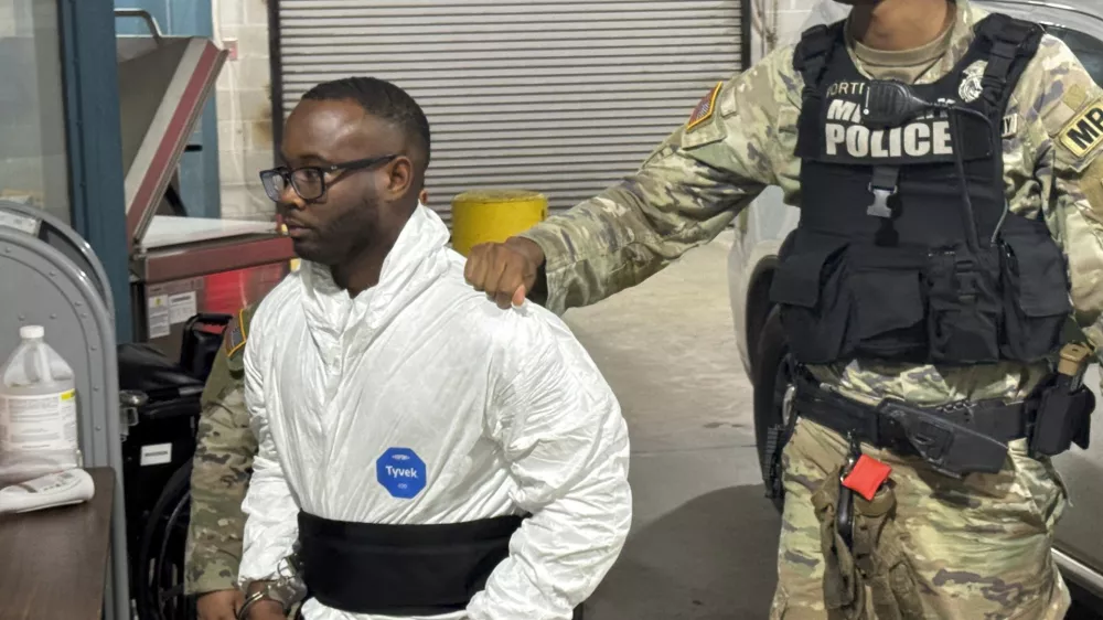 Sgt. Quornelius Radford, a suspect in the shooting of five soldiers at Fort Stewart, is escorted by military police into a booking room at the Liberty County Jail in Hinesville, Ga., Wednesday, Aug. 6, 2025. (AP Photo/Lewis M. Levine)