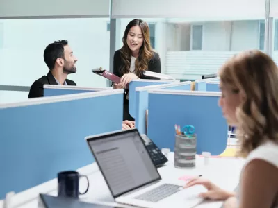 Teamwork with colleagues working and talking in modern office. Busy girl, man and woman at work in coworking space and meeting as co-workers. Business people, worker, job and profession
