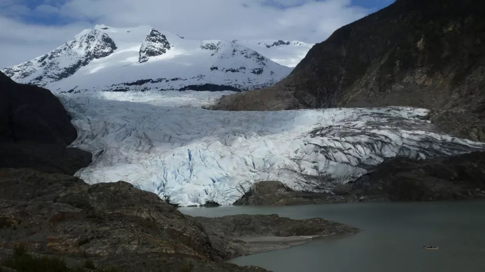 FILE - A canoe, bottom right, glides on Mendenhall Lake, in front of the Mendenhall Glacier, on Sunday, May 18, 2025, in Juneau, Alaska. (AP Photo/Becky Bohrer, File)