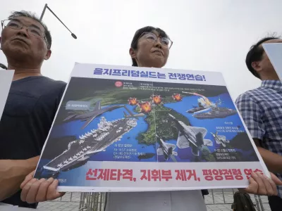 South Korean protesters attend a rally to oppose the planned joint military exercises called Ulchi Freedom Shield,or UFS, between the U.S. and South Korea, outside the presidential office in Seoul, South Korea, Monday, Aug. 11, 2025. The signs at bottom read, "Ulchi Freedom exercise is a war." (AP Photo/Ahn Young-joon)
