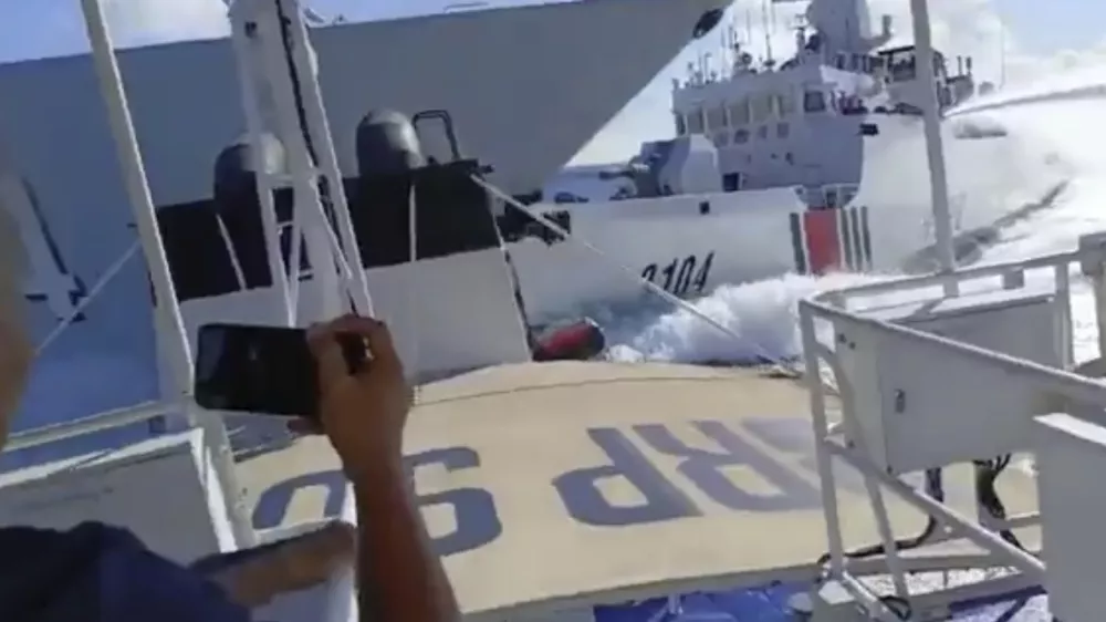 In this photo grab from video provided by the Philippine Coast Guard, a Chinese Navy vessel, left, accidentally collides with a Chinese Coast Guard ship, right, while chasing a Philippine fisheries boat, foreground, near Scarborough Shoal in the disputed South China Sea on Monday, Aug. 11, 2025. (Philippine Coast Guard via AP)