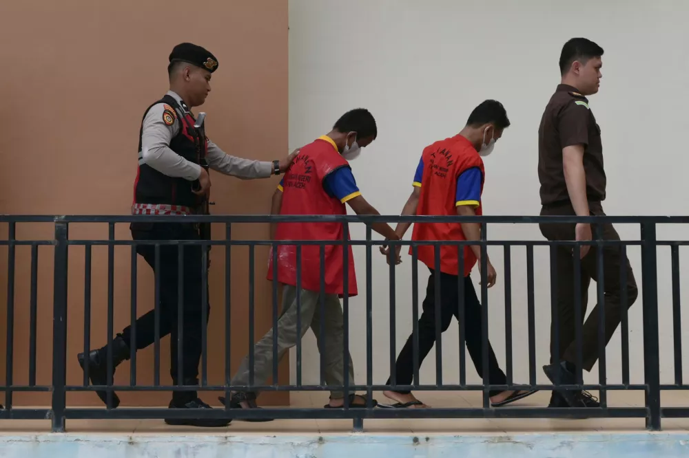 A police officer and a prosecutor escort two men accused of having gay sex, upon arrival for their sentencing hearing at the Sharia Court in Banda Aceh, Indonesia, Monday, Aug. 11, 2025. (AP Photo/Reza Saifullah)