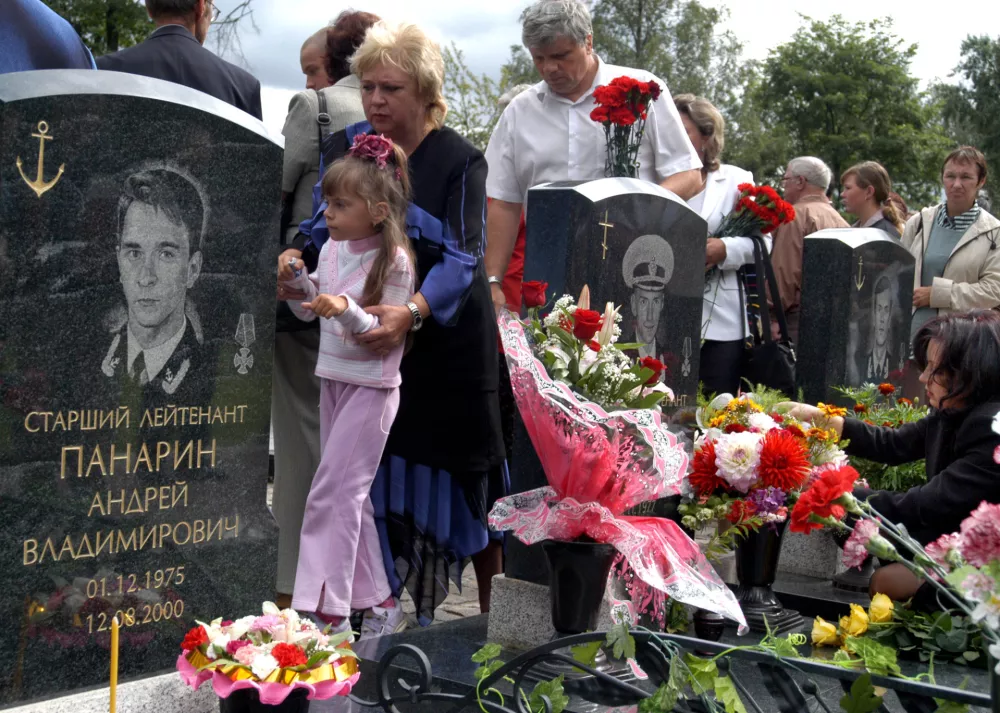 Relatives, no names given, of crew members of the Kursk nuclear submarine, stand near the gravestones of the submariners during a ceremony to commemorate the fifth anniversary of the sinking, at the Serafimovskoye Memorial Military Cemetery in St.Petersburg, Friday, Aug. 12, 2005. The Kursk nuclear submarine was conducting military exercises in the Barents sea on Aug. 12, 2000, when it was shaken by explosions that sent the vessel to the sea floor. 118 seamen died aboard the vessel. (AP Photo/Alexander Belenky)
