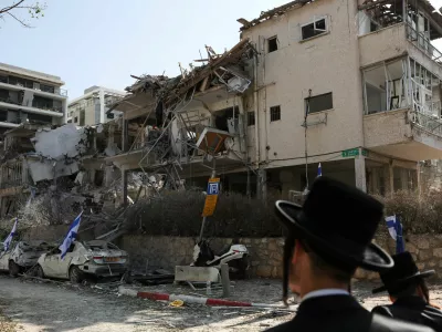 People look at damaged buildings at an impact site following missile attack from Iran on Israel, in Ramat Gan, Israel, June 14, 2025. REUTERS/Ronen Zvulun