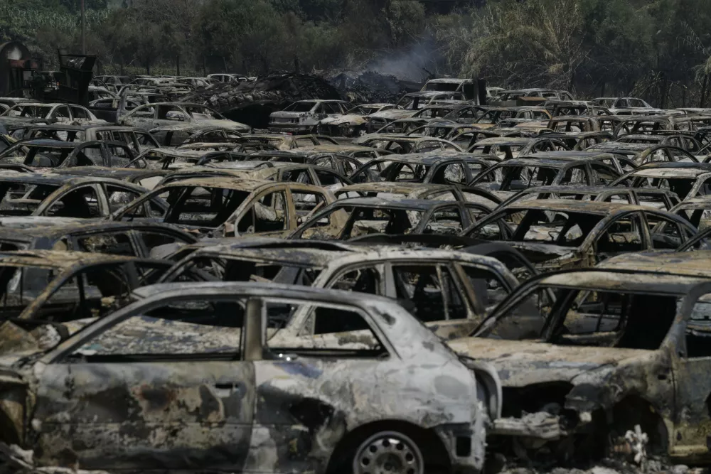 Burned cars are seen at an impound lot in Kato Achaia, during a wildfire near Patras city, western Greece, Wednesday, Aug. 13, 2025. (AP Photo/Thanassis Stavrakis)