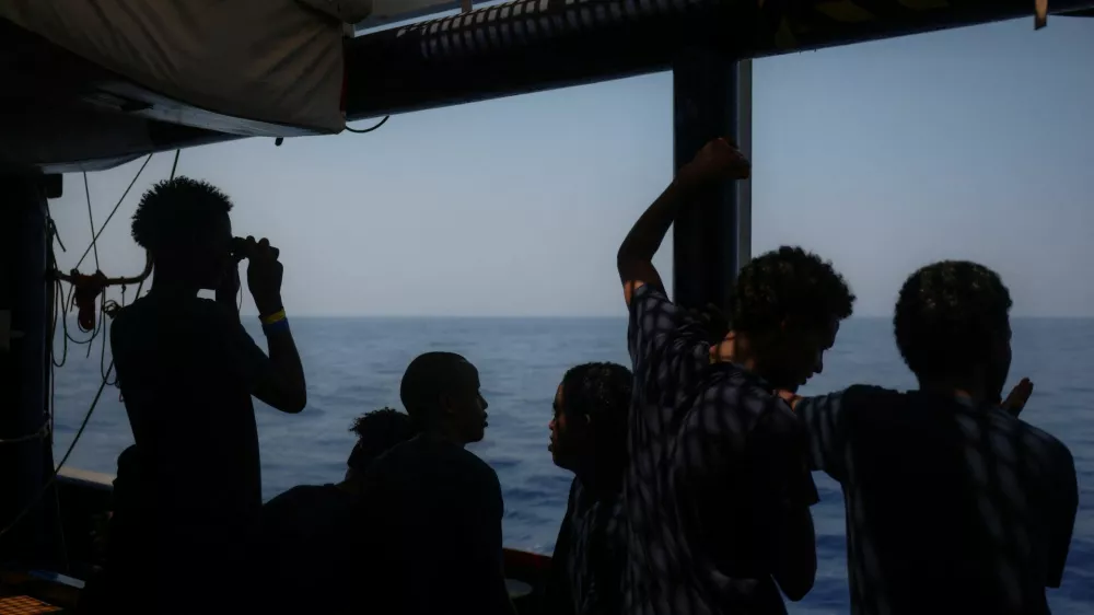A young migrant looks for land through binoculars, aboard the migrant search and rescue ship Sea-Watch 5, operated by German NGO Sea-Watch, as the ship makes its way towards the designated port of Salerno, Italy, August 13, 2025. REUTERS/Louisa Gouliamaki