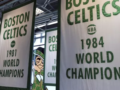 FILE - Lucky the Leprechaun, the Boston Celtics team logo, peers out from in between Celtics championship banners hanging in their new basketball team practice facility, Tuesday, June 19, 2018, in Boston. (AP Photo/Elise Amendola, File)
