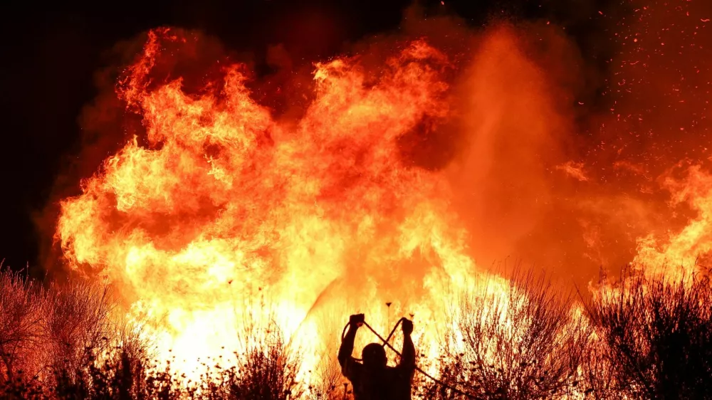 A firefighter works as wildfire continues to burn in Delvina, Albania, August 12, 2025. REUTERS/Florion Goga