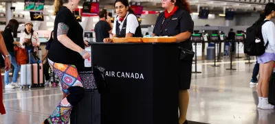Air Canada workers speak with a passenger at a kiosk to deal with flight disruptions, ahead of a potential strike by flight attendants of the airline, at the Toronto Pearson International Airport in Mississauga, Ontario, Canada, August 15, 2025. REUTERS/Cole Burston