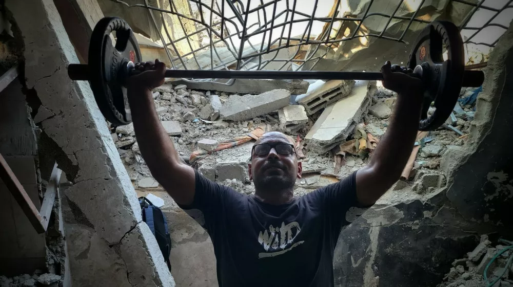 KHAN YUNIS, GAZA - JULY 21: A Palestinian man weightlifts in a gym, which has been damaged due to Israeli attacks, as Palestinian people try to exercise with limited opportunities of bodybuilding equipment in Khan Yunis, Gaza on July 21, 2024. Hani Alshaer / Anadolu,Image: 891889870, License: Rights-managed, Restrictions:, Model Release: no