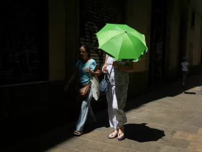 A woman carries an umbrella for shade from the heat as she walks around El Born, in Barcelona, Spain, August 9, 2025. REUTERS/Bruna Casas