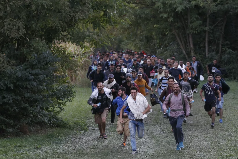 ﻿FILE - In this Sept. 20, 2016 file photo, migrants run as they cross the border from Croatia near the village of Zakany, Hungary. In a year when more than a million people arrived on European shores, UNHCR said Monday, June 20, 2016 that continued conflicts and persecution in places like Syria and Afghanistan fueled a nearly 10-percent increase in the total number of refugees and internally displaced people in 2015.((AP Photo/Petr David Josek, File)