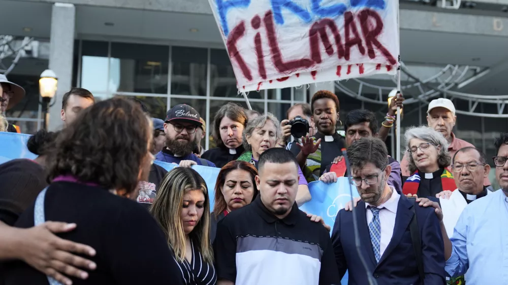 Jennifer Vasquez Sura, front left, her husband Kilmar Abrego Garcia, front center, and Attorney Simon Sandoval-Moshenberg, front right, attend a protest rally at the Immigration and Customs Enforcement field office in Baltimore, Monday, Aug. 25, 2025, to support Kilmar Abrego Garcia. (AP Photo/Stephanie Scarbrough)