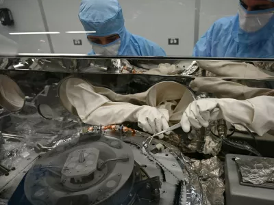 Strokovnjaka za obdelavo astromaterialov, Mari Montoya (levo) in Curtis Calva (desno), z orodjem zbirata delce asteroida z dna znanstvenega vsebnika misije OSIRIS-REx. / Foto: Nasa