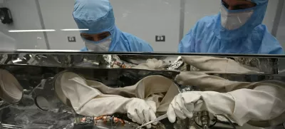 Strokovnjaka za obdelavo astromaterialov, Mari Montoya (levo) in Curtis Calva (desno), z orodjem zbirata delce asteroida z dna znanstvenega vsebnika misije OSIRIS-REx. / Foto: Nasa