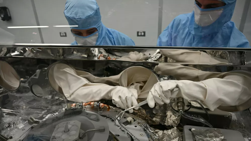 Strokovnjaka za obdelavo astromaterialov, Mari Montoya (levo) in Curtis Calva (desno), z orodjem zbirata delce asteroida z dna znanstvenega vsebnika misije OSIRIS-REx. / Foto: Nasa